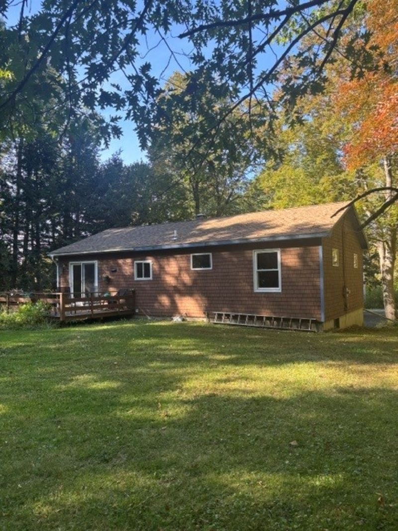 Back of the house with deck and a large open lawn